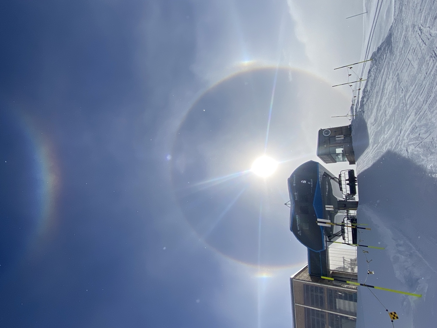 A full sun halo ringing the sky above a mountain lift
